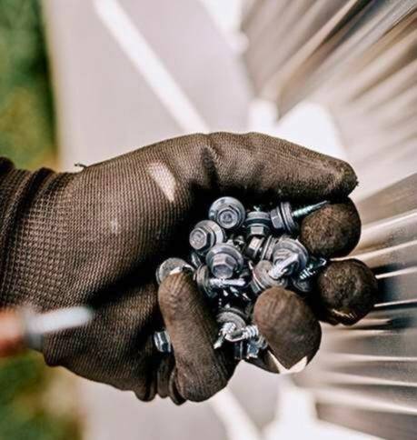 Mão com luva segurando parafusos especiais usados em aplicações industriais de fixação